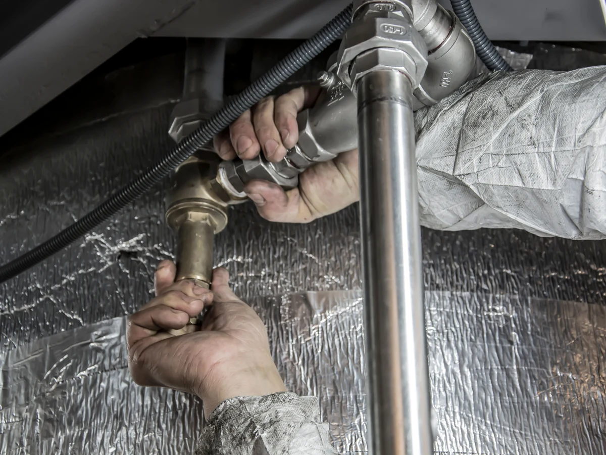 General Facility Plumbing Stock Photograph Close-up of hands fitting steel plumbing connections with tools